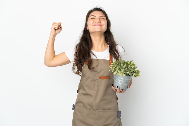 Jong Russisch tuinmanmeisje dat een geïsoleerde plant houdt die sterk gebaar doet