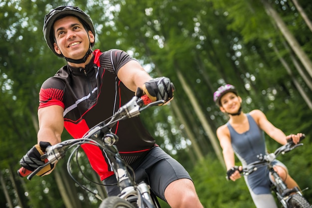 Jong sportief paar die op fietsen bij de bosweg berijden.