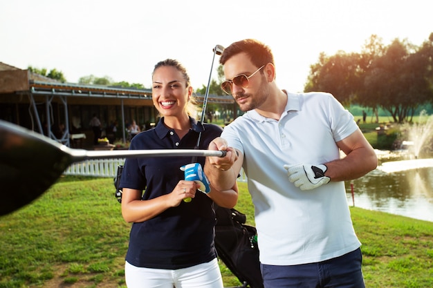 Foto jong sportief paar golfen op een golfbaan.