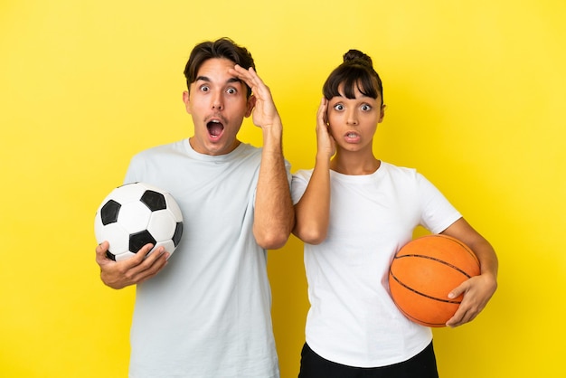 Jong sportpaar dat voetbal en basketbal speelt, geïsoleerd op een gele achtergrond, heeft net iets gerealiseerd en heeft de oplossing voor ogen