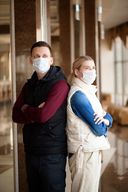 Jong stel dat medische maskers draagt in een luchthavenlounge