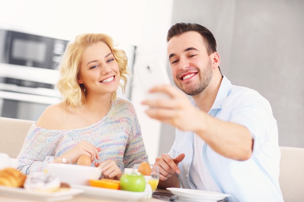 jong stel dat ontbijt eet in de keuken en selfie neemt