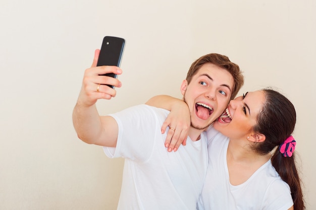 Jong stel doet selfie met je telefoon glimlachend, lachend en voor de gek houdend