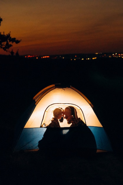 Jong stel, een jongen en een meisje met felgekleurde gebreide mutsen stopten op een camping bij het vuur