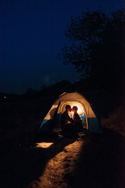 Jong stel, een jongen en een meisje met felgekleurde gebreide mutsen stopten op een camping bij het vuur