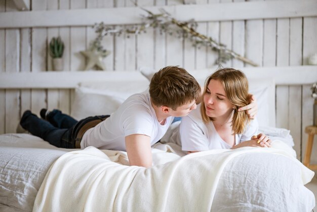 Jong stel een jongen en een meisje van blanke etniciteit knuffelen in bed en zoenen