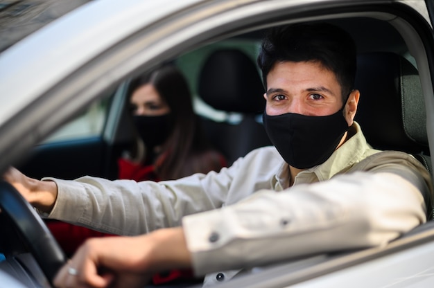 Jong stel in een auto met beschermende maskers tegen covid 19 coronavirus pandemie