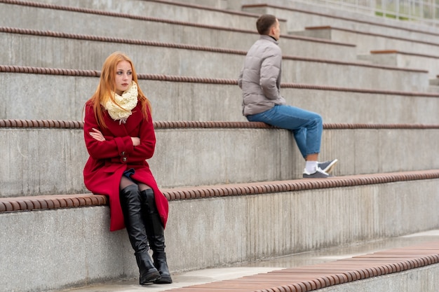 Jong stel in een ruzie, een jongen en een meisje zitten in verschillende richtingen te kijken in de lege tribunes