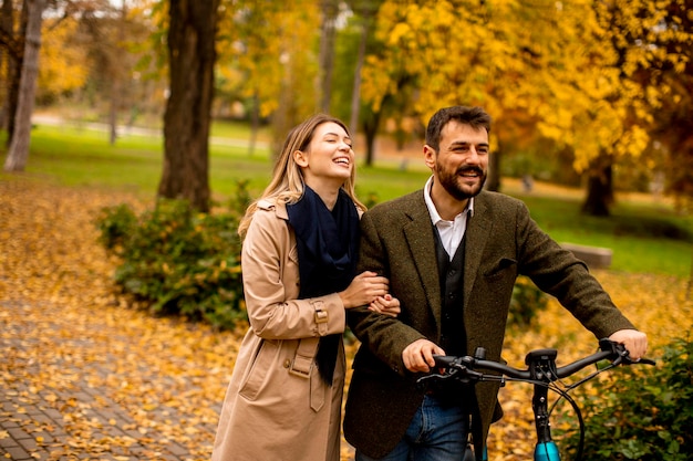 Jong stel in het herfstpark met elektrische fiets