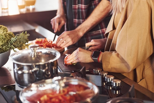 Jong stel in vrijetijdskleding die samen in de keuken staat en voedsel bereidt