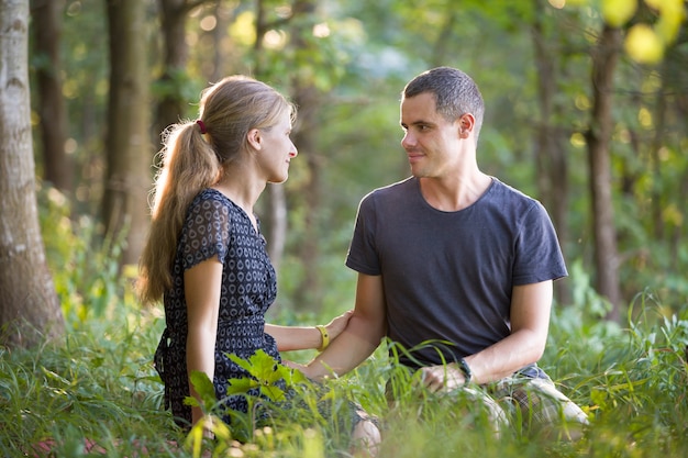 Jong stel, man en vrouw zitten samen buiten genieten van de natuur.