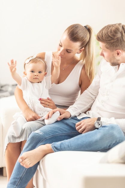 Jong stel met een babymeisje dat haar armen omhoog houdt en thuis speelt.