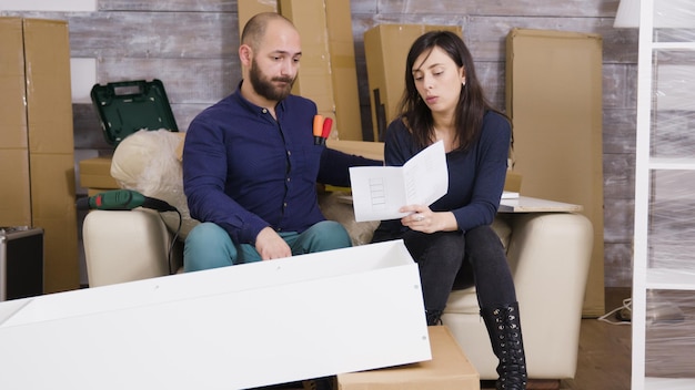 Jong stel monteert een plank als een team in hun nieuwe appartement en leest instructies.