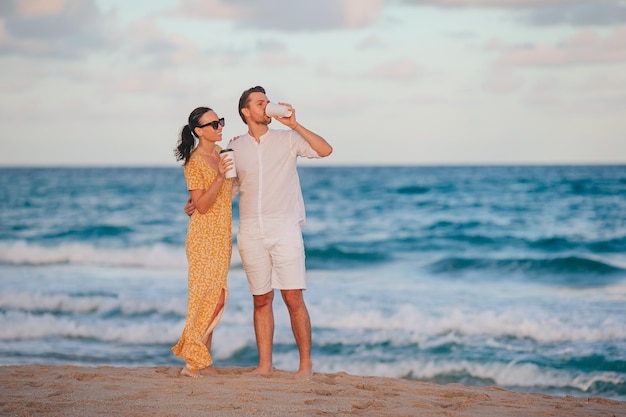 Jong stel op het strand wakker en geniet van koffie om mee te nemen