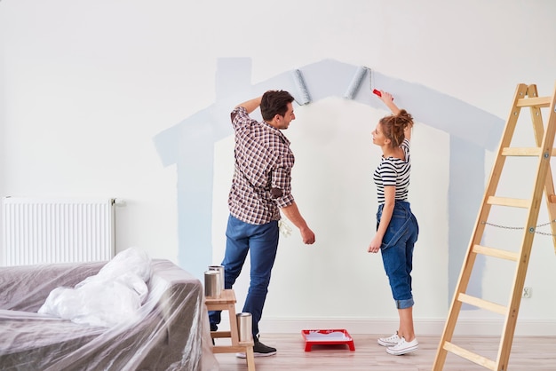 Jong stel schildert de binnenmuur in hun nieuwe appartement