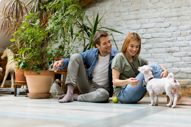 Foto jong stel zit op de vloer van de rustieke woonkamer en spelen met de hond