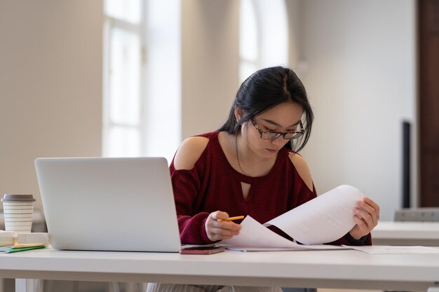 Jong studentenmeisje dat in campusstudie werkt, bereidt zich voor op examen of serieuze test aan universiteit of hogeschool