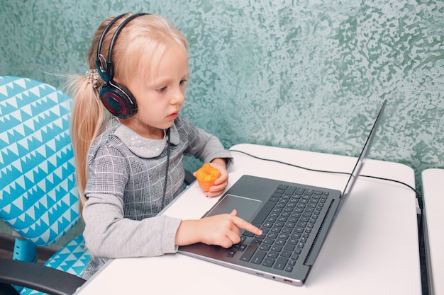 Jong studentenmeisje met wortel in de hand typend laptop toetsenbord lerend en voorbereidend terug naar school