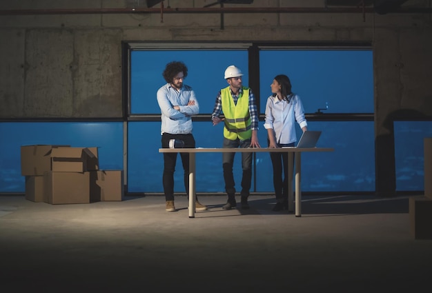 Foto jong team van zakenmensen in groep, architect en ingenieur op bouwplaats die documenten en zakelijke workflow controleren met behulp van laptopcomputer in nieuw startkantoor