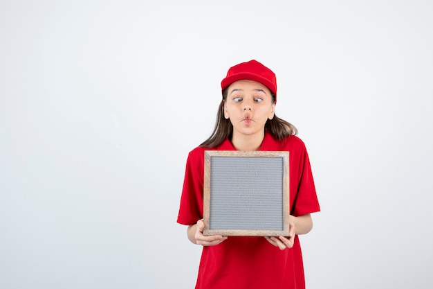 jong tienermeisje in rood uniform staan ?? en houden frame