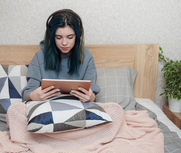 Jong tienermeisje met blauw haartablet en hoofdtelefoons