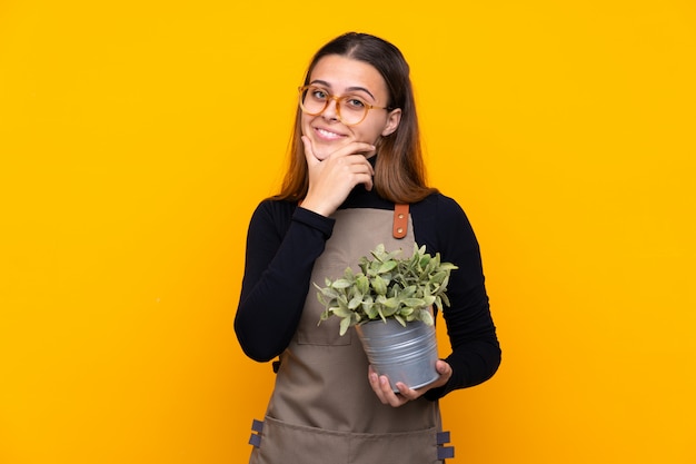 Jong tuinmanmeisje die een installatie over geïsoleerd houden geel denkend een idee