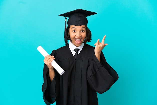 Jong universitair gediplomeerd meisje dat over geïsoleerde blauwe achtergrond hoorngebaar maakt