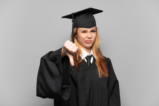 Jong universitair gediplomeerd meisje over geïsoleerde achtergrond die duim omlaag met negatieve uitdrukking toont