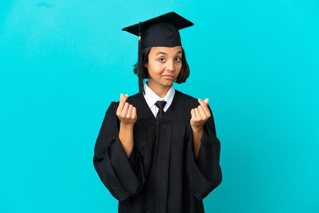 Jong universitair gediplomeerd meisje over geïsoleerde blauwe achtergrond die geldgebaar maakt