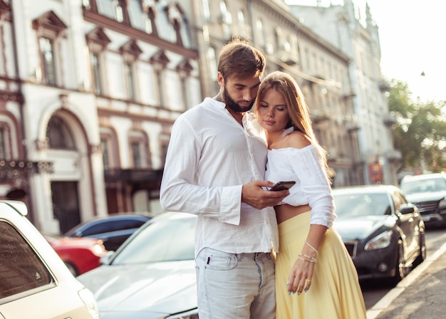 Jong verliefd koppel kijkt naar het scherm van de smartphone in de stad