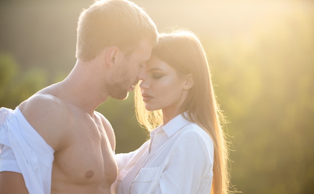 Jong verliefd stel brengt samen tijd door bij zonsondergang man omhelst en gaat sensuele vrouw kussen