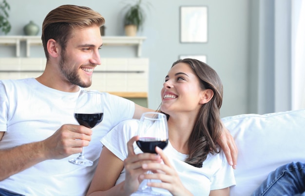 Jong verliefd stel dat een glas rode wijn drinkt in hun woonkamer