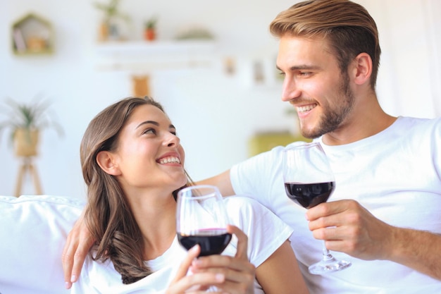 Jong verliefd stel dat een glas rode wijn drinkt in hun woonkamer