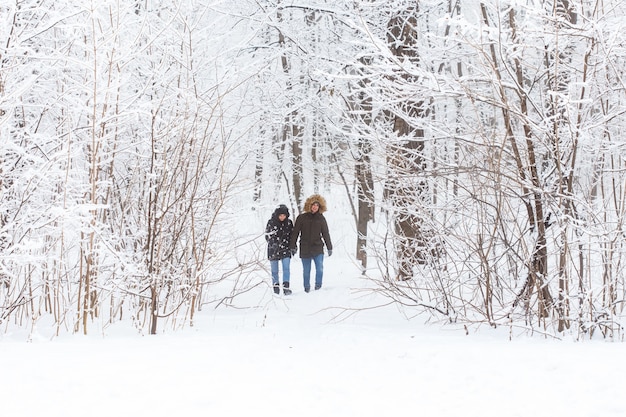 Jong verliefd stel loopt in het besneeuwde bos. Actieve wintervakanties.