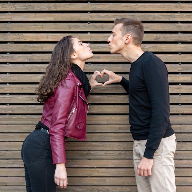 Jong verliefd stel maakt de vorm van het hart met hun handen terwijl ze elkaars liefjes kussen Liefdesverhaal Valentijnsdag concept