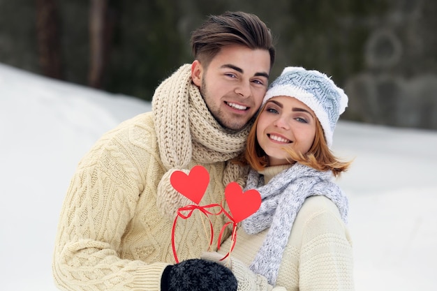 Jong verliefd stel met rode papieren harten buiten in de winter