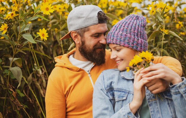 Jong verliefd stel omhelst elkaar in het herfstpark met bloemen Liefdesverhaal