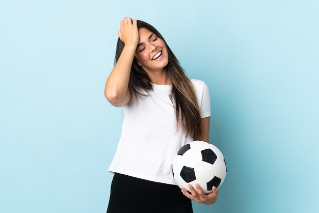 Jong voetballer Braziliaans meisje dat op blauwe achtergrond wordt geïsoleerd die veel glimlachen