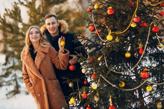 Jong volwassen koppel siert kerstboom in winter bos nieuwjaar dennen vakantie feest viering