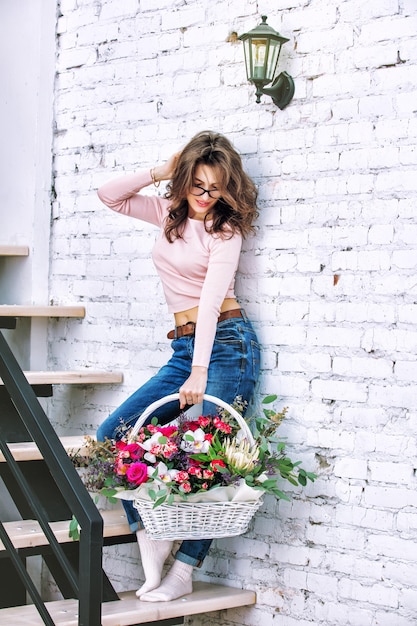 Jong volwassen mooi en gelukkig vrouwenmodel met bloemen in haar handenportret op een heldere trap