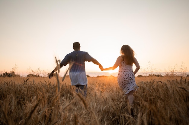 Jong volwassen stel hand in hand tijdens het wandelen in het veld