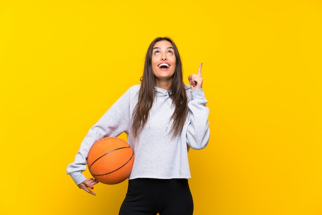 Jong vrouwen speelbasketbal dat op geel wordt geïsoleerd dat een groot idee benadrukt