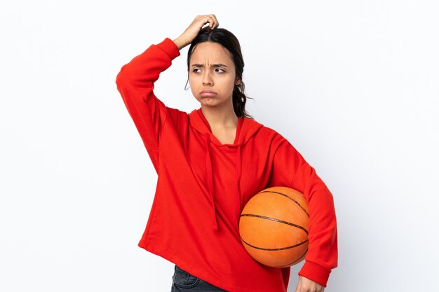 Jong vrouwen speelbasketbal over witte muur die twijfels hebben terwijl krassend hoofd