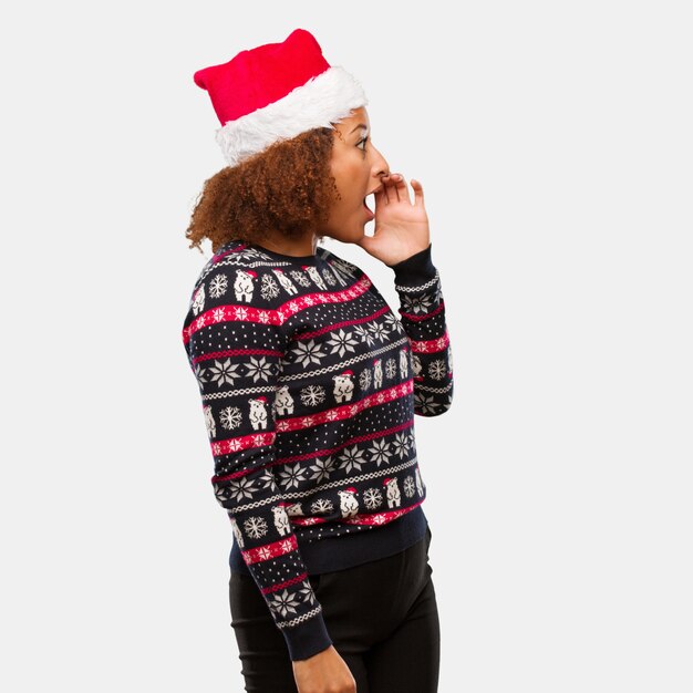 Jong zwarte in een trendy Kerstmissweater met druk fluisteren roddel ondertoon