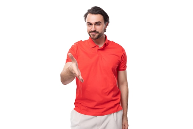 Jonge aangename vriendelijke man met zwart haar en baard gekleed in een rood T-shirt op een witte achtergrond