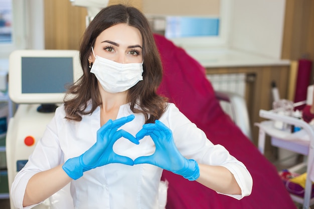 Jonge aantrekkelijke arts vrouw binnenshuis. Portret van vrouw die medisch uniform in de kliniek draagt. Arts met medische apparatuur. Cosmetologist in haar salon