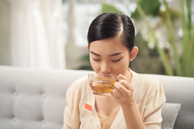 Jonge aantrekkelijke aziatische vrouw die thee drinkt?