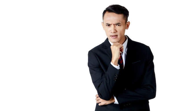 Jonge aantrekkelijke Aziatische zakenman dragen zwart pak met wit overhemd en stropdas doen de denkende pose met nieuwsgierig gezicht en hand op zijn kin op witte achtergrond geïsoleerd