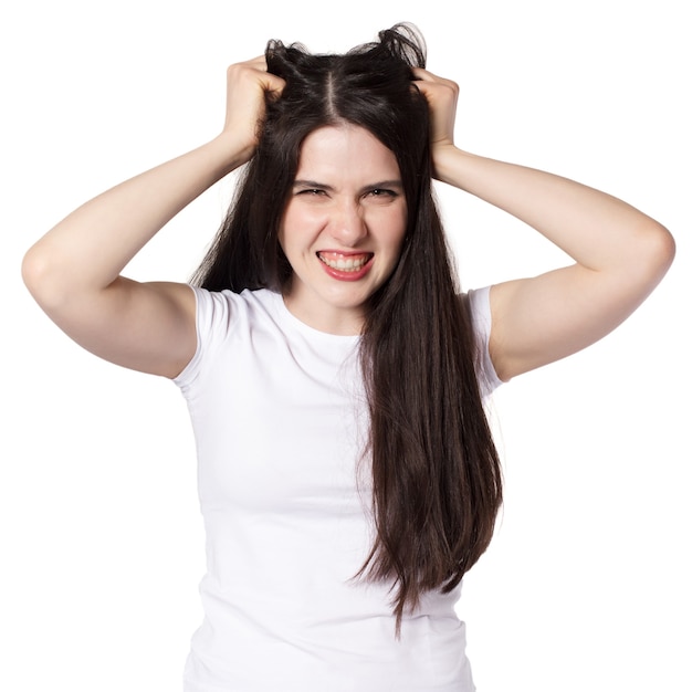 Jonge aantrekkelijke blanke zwartharige brunette vrouw in wit t-shirt, handen gegrepen en aan haar haren trekken, woede vrouw concept idee