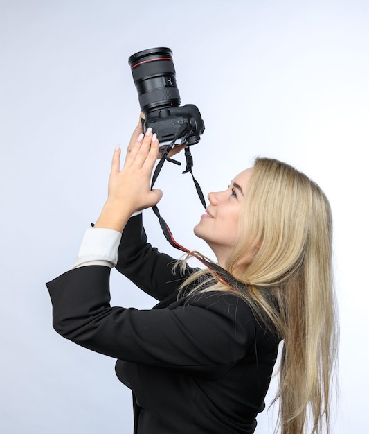 Jonge aantrekkelijke blonde vrouw met moderne DSLR-camera's die foto's nemen op witte achtergrond